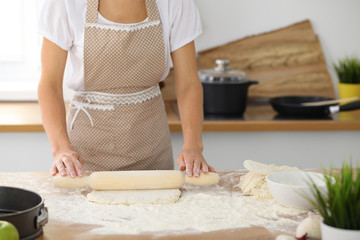 Female hands making dough for pizza or bread while using rolling pin. Baking concept