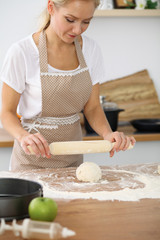 Female hands making dough for pizza or bread while using rolling pin. Baking concept