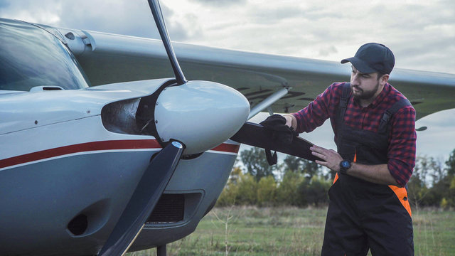 Aircraft mechanic polishing plane and then standing satisfied with his job.