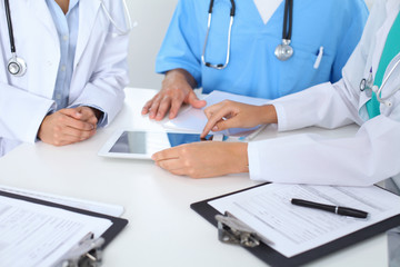 Group of doctors at medical meeting. Close up of physician using touch pad or tablet computer