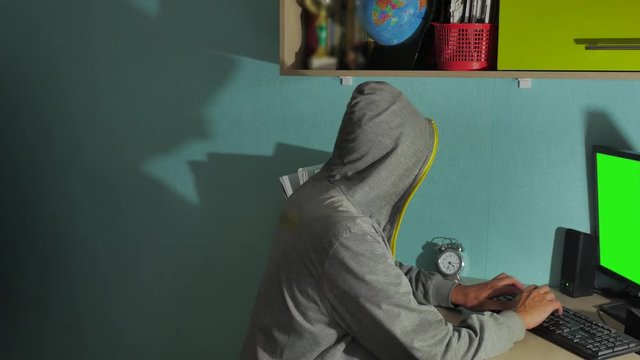 Male hacker working on a computer. man hacker in hood hiding his face