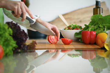 Closeup of human hands cooking vegetables salad in kitchen on the glass  table with reflection