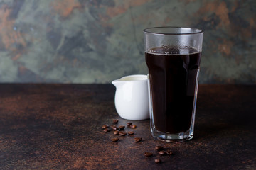 A glass of hot coffee espresso on dark background with coffee beans