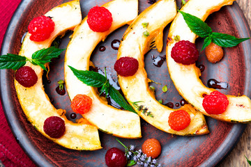 Grilled pumpkin with honey, raspberry and mint on wooden rustic background. Top view. Close up.