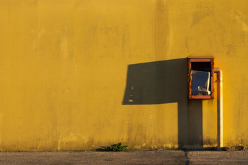 Fire extinguisher shadow on a yellow wall (Pesaro, Italy) - 179246408