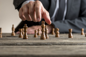 Businessman wearing business suit playing a game of chess - obrazy, fototapety, plakaty