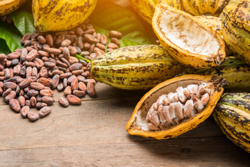Cocoa beans and cocoa pod on a wooden surface.