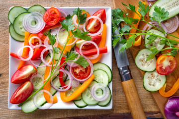 Sliced fresh vegetables on a white plate with a knife