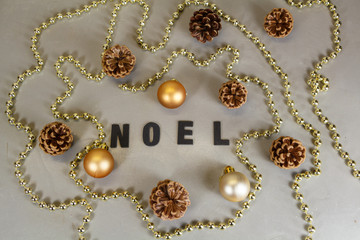 Boules de Noël, pommes de pin et guirlande de perles autour du mot Noël