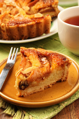 Freshly baked hot apple pie served on a yellow plate with tea          