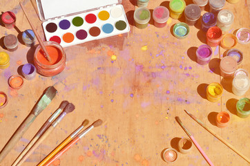 Still life with a lot of brushes and jars of watercolor and gouache paint