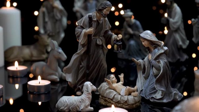 Christmas manger nativity scene with figures and atmospheric candles lights. Dolly shot in 4k.