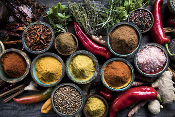 A selection of various colorful spices on a wooden table in bowls