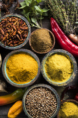 A selection of various colorful spices on a wooden table in bowls