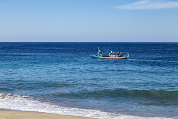Obraz premium A fishing boat sails down beach in Paga, Indonesia.