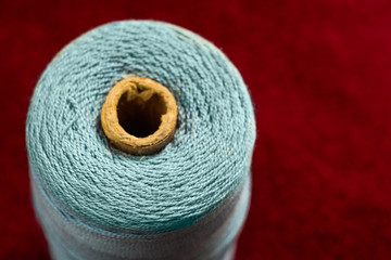 Coil with blue threads on a red background, soft focus