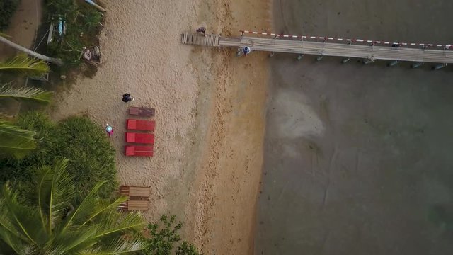 Camera starts on closeup of sand and then going straight up reveals an island paradise in southeast Asia on the Koh Tonsay, Rabbit Island in Cambodia.