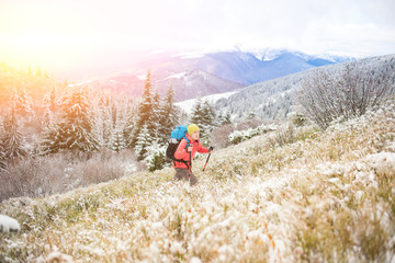 Girl with backpack walking on snow in the mountains.