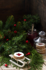 Linzer cookies in a Christmas decoration on a wooden surface.