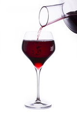 A beautiful big glass with red wine. The wine pours out of the decanter into the glass. isolated