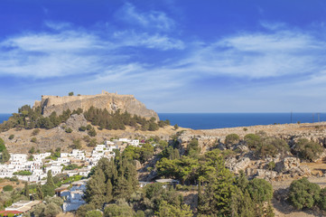 Fototapeta na wymiar Castle view Acropolis of city Lindos of Rhodes island with big blue cloudy sky