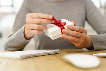 frau am schreibtisch packt ein kleines geschenk aus