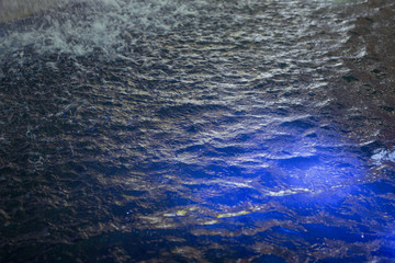 Obraz premium water stream coming out from simulate water fall with blue light under