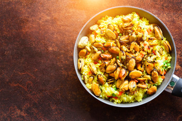 Traditional spanish seafood paella in pan rice, peas, shrimps, mussels, squid on rustic dark background. Top view, copyspace