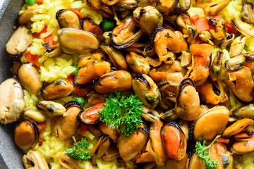 Traditional spanish seafood paella in pan rice, peas, shrimps, mussels, squid on light grey concrete background. Top view, copyspace