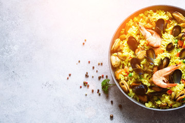 Traditional spanish seafood paella in pan rice, peas, shrimps, mussels, squid on light grey...