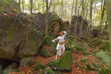 A model gets dressed up in white vintage fashion clothes. She decorates herself with Autumn leaves...