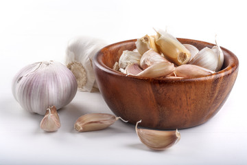 Organic grown garlic in a wooden bowl on a white background