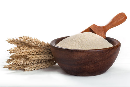 wheat semolina in a wooden bowl on a white table