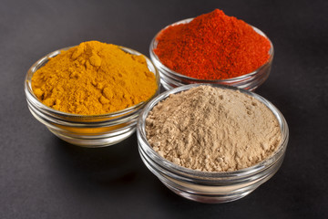 spices from ginger, turmeric and red peppers on a black background