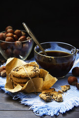 A cup of black coffee with nuts and cookies on a blue linen napkin. Flat lay