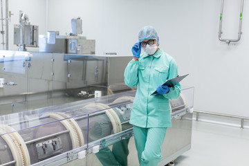 factory worker stand near machine with tablet