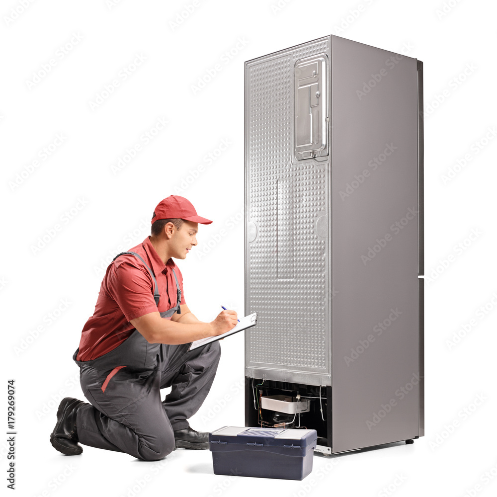 Poster Repairman kneeling behind a fridge and writing in a clipboard