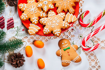 Christmas gingerbread cookies homemade on red plate with branches of Christmas tree and decor on home New Year table. Merry Christmas postcard