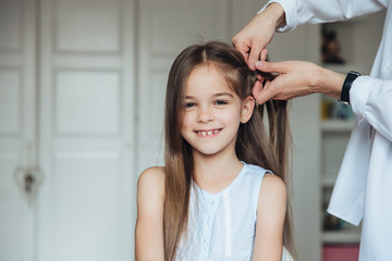 Mother braiding cheerful little girl