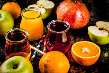 Fresh fruit and juices variety. Oranges, pomegranate and apples. Dark rusty background, copy space