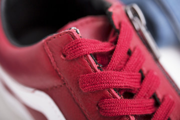 Fashion shoes with shoestring. Red sneaker and shoelace on white background