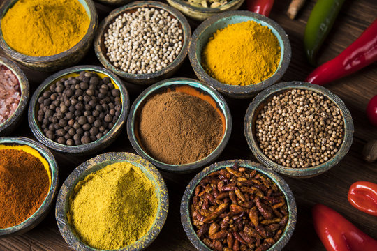 A selection of various colorful spices on a wooden table in bowls