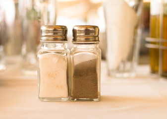 salt pepper traditional seasoning in transparent glass vessels with chrome top on a blurred background