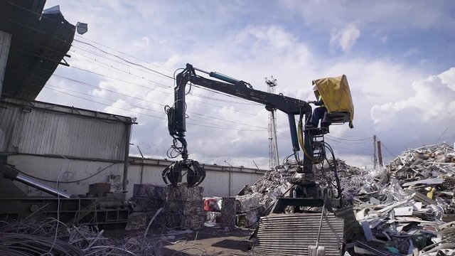 Scrap yard with crane and cars crushed into small cubes