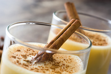 Close up homemade eggnog with cinnamon on wooden table. Typical Christmas dessert.