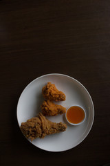 Fried chicken and sauce on a white plate, Close-up fried chicken on table low light or underexposed