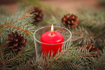 New Year's composition. Burning red candle on spruce branches with fir cones. Christmas.