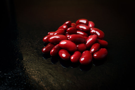 Red beans on a black background with drops of water