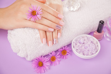 Obraz na płótnie Canvas Beautiful pink and silver manicure with flowers and spa essentials