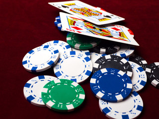 Cards and poker chips on a red background. A strong hand of two Kings and a lot of chips.